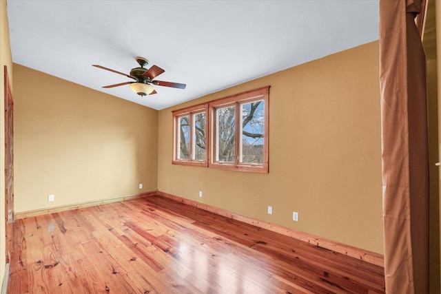 spare room featuring baseboards, light wood finished floors, and ceiling fan