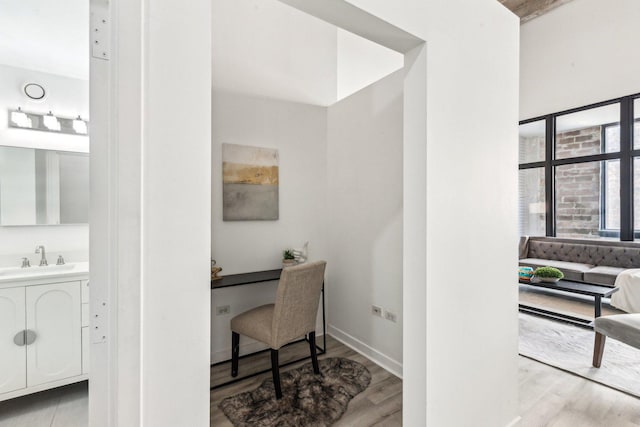 office with light wood-style floors, a sink, and baseboards