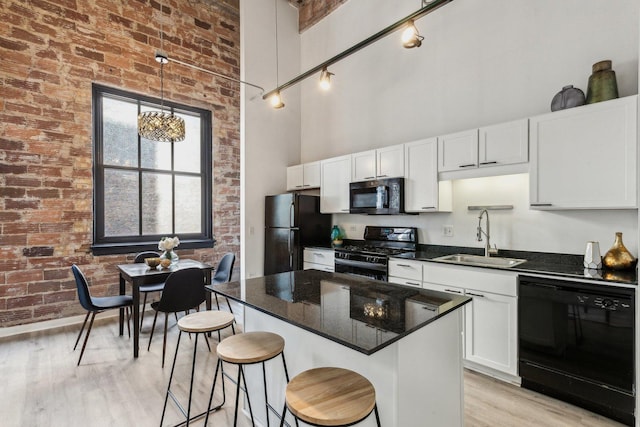 kitchen with pendant lighting, a high ceiling, white cabinets, a sink, and black appliances