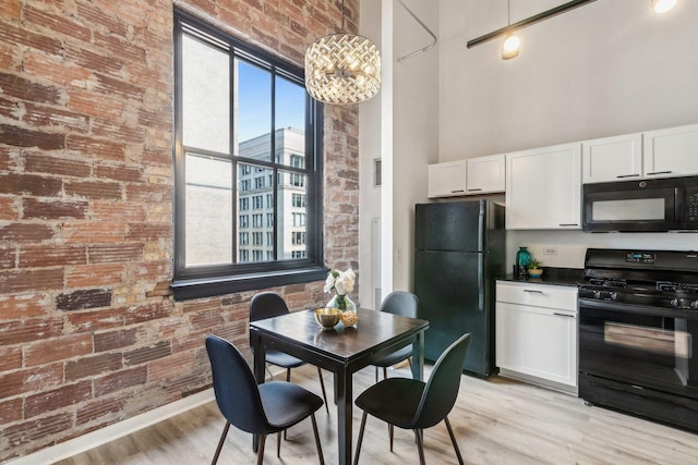 kitchen with black appliances, dark countertops, a towering ceiling, and white cabinetry