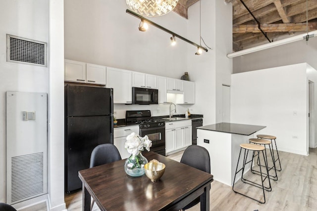 kitchen featuring a high ceiling, visible vents, white cabinets, black appliances, and dark countertops