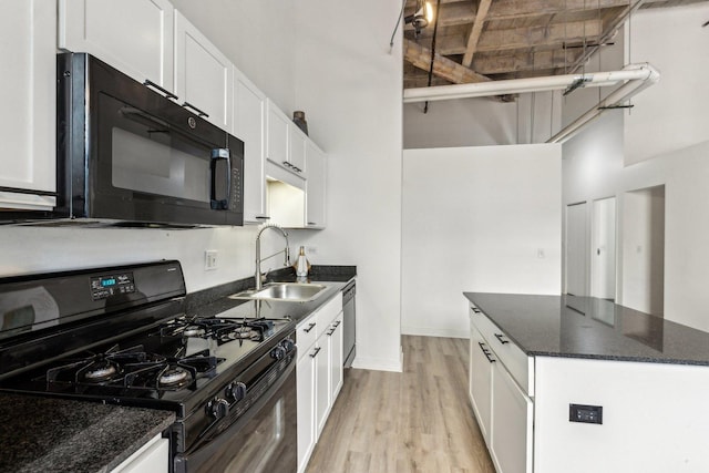 kitchen with black appliances, a high ceiling, white cabinets, and a sink