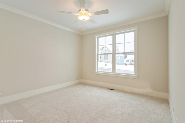 carpeted spare room featuring a ceiling fan, visible vents, crown molding, and baseboards