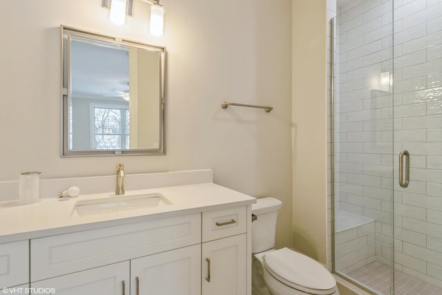 bathroom featuring a ceiling fan, a shower stall, toilet, and vanity