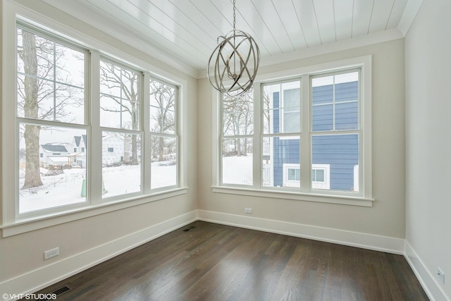 unfurnished dining area featuring dark wood-type flooring, a chandelier, ornamental molding, and baseboards