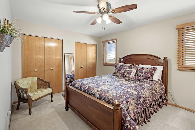 bedroom with light carpet, two closets, and ceiling fan