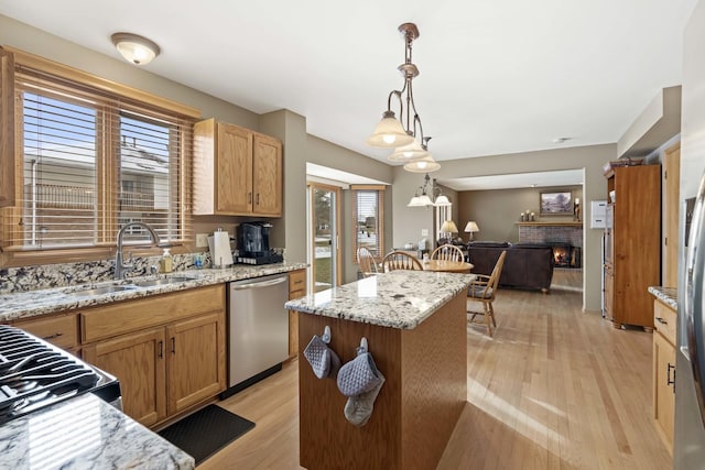 kitchen featuring light wood-type flooring, stainless steel dishwasher, pendant lighting, a center island, and sink