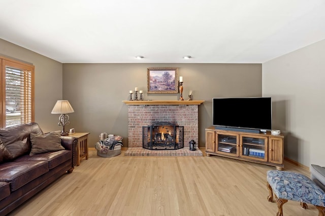 living room with a brick fireplace and light wood-type flooring