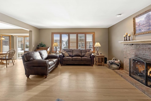 living room featuring a brick fireplace and light wood-type flooring