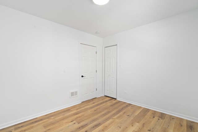 unfurnished room with light wood finished floors, baseboards, and visible vents