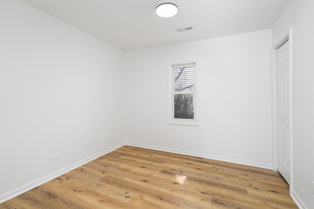 spare room with baseboards, visible vents, and wood finished floors