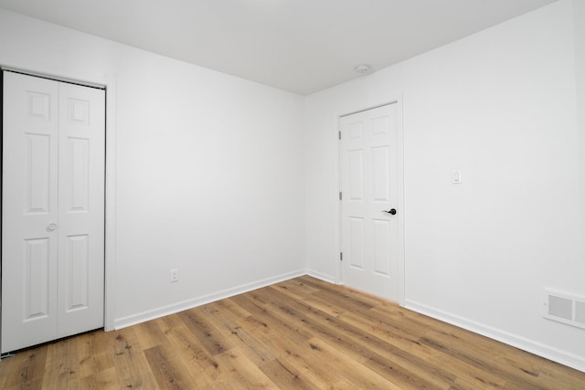 unfurnished bedroom with wood finished floors, visible vents, and baseboards