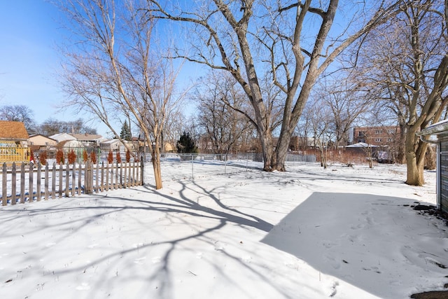 yard layered in snow featuring fence and a residential view