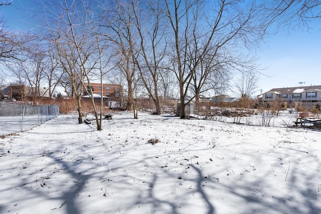 yard covered in snow with a residential view and fence