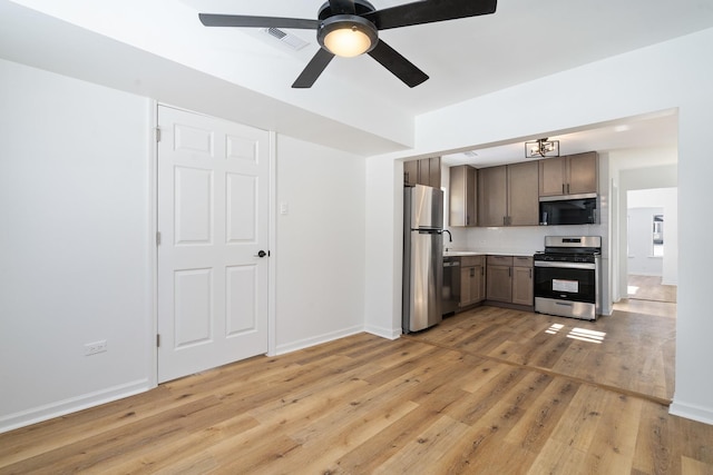 kitchen with light wood finished floors, baseboards, stainless steel appliances, and light countertops