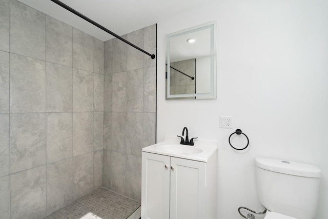 bathroom featuring toilet, a tile shower, and vanity