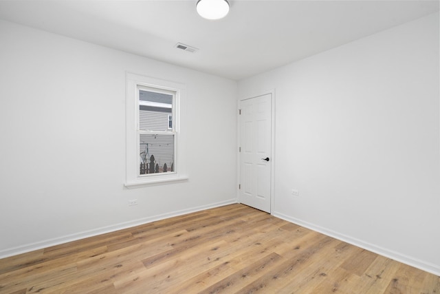 empty room with visible vents, light wood-style flooring, and baseboards