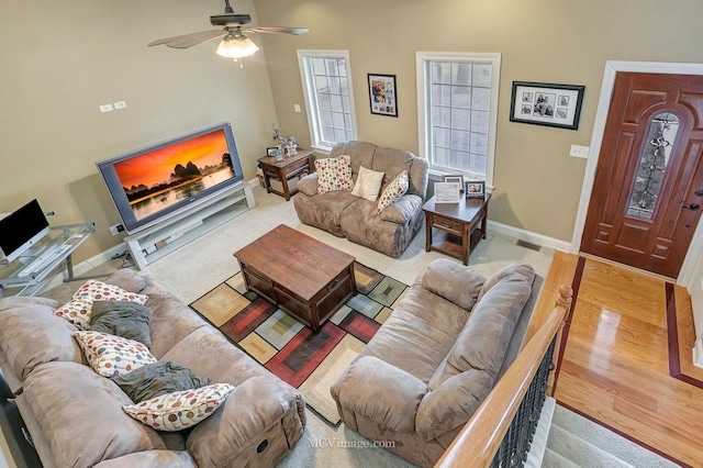 living room featuring visible vents, ceiling fan, baseboards, and wood finished floors