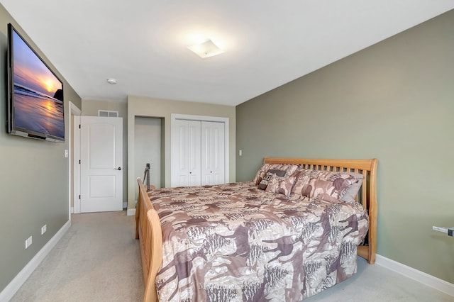 bedroom with a closet, light carpet, visible vents, and baseboards