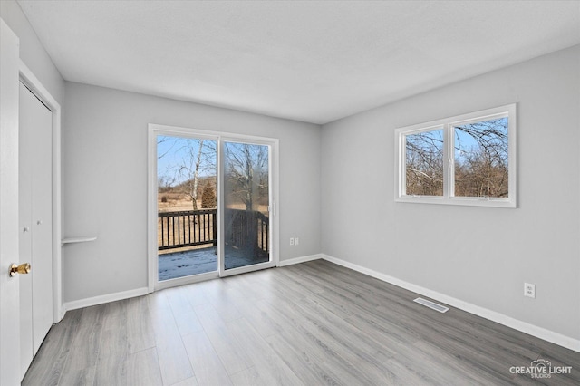 unfurnished bedroom with wood-type flooring, access to exterior, and a textured ceiling