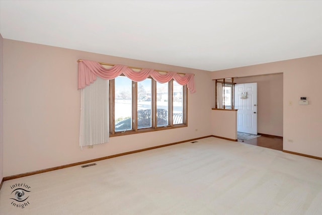 unfurnished room with carpet floors, baseboards, and visible vents