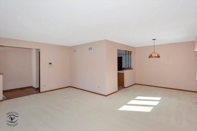 unfurnished room with light carpet, visible vents, and baseboards