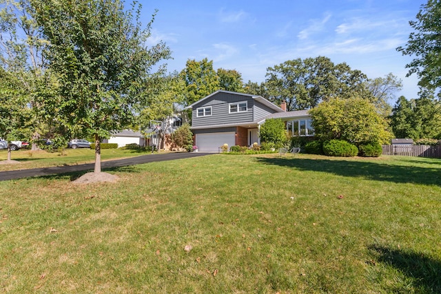 tri-level home with a front lawn, aphalt driveway, fence, a garage, and a chimney