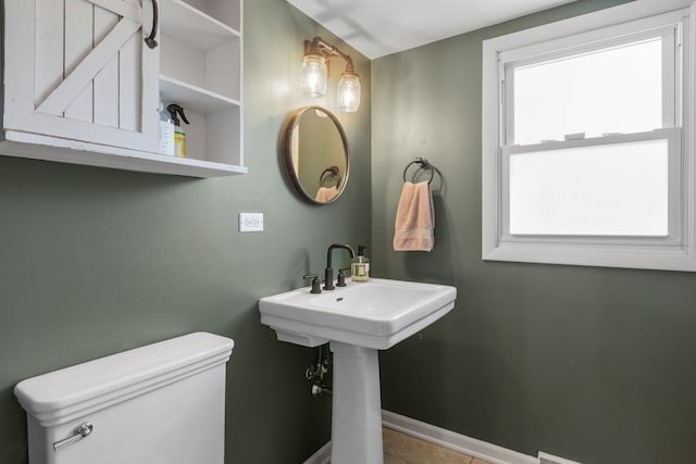 half bathroom with a sink, baseboards, and toilet