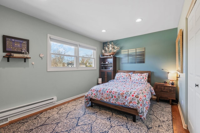 bedroom with recessed lighting, a baseboard heating unit, baseboards, and wood finished floors