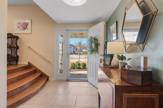 entryway featuring stairway, plenty of natural light, baseboards, and light tile patterned flooring