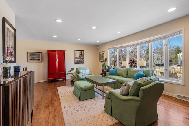 living area with recessed lighting, wood finished floors, visible vents, and baseboards