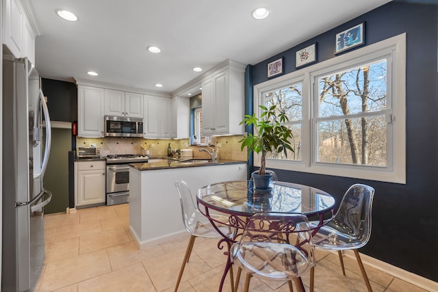 kitchen with stainless steel appliances, dark countertops, decorative backsplash, and white cabinetry