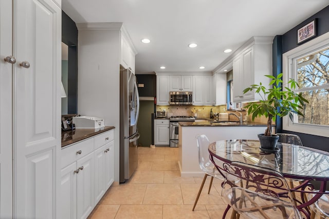 kitchen with dark countertops, light tile patterned floors, white cabinetry, and stainless steel appliances