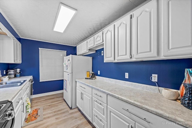 kitchen featuring black range with electric stovetop, a sink, light wood-style floors, white cabinets, and freestanding refrigerator