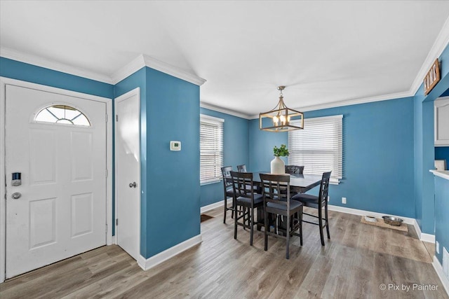 dining room featuring baseboards, a notable chandelier, wood finished floors, and crown molding