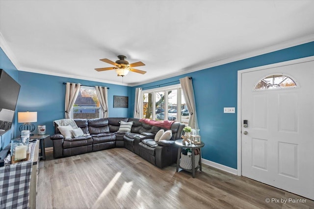 living area with ornamental molding, a wealth of natural light, baseboards, and wood finished floors