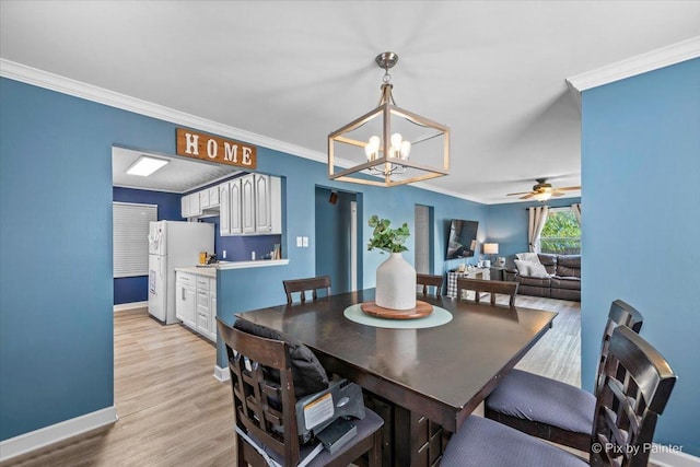 dining space with ornamental molding, light wood-style flooring, baseboards, and an inviting chandelier