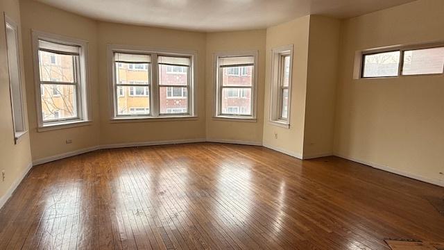 unfurnished room featuring plenty of natural light, baseboards, and dark wood-style flooring