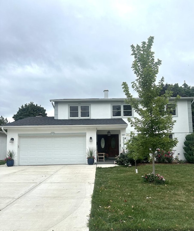 traditional-style house featuring a front yard, concrete driveway, and stucco siding