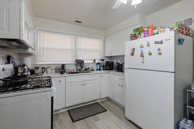 kitchen with white appliances, white cabinetry, light countertops, and light wood-style floors