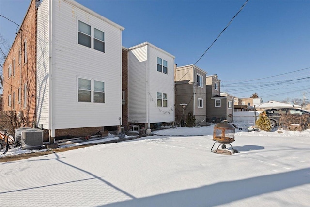 snow covered property with cooling unit and a residential view