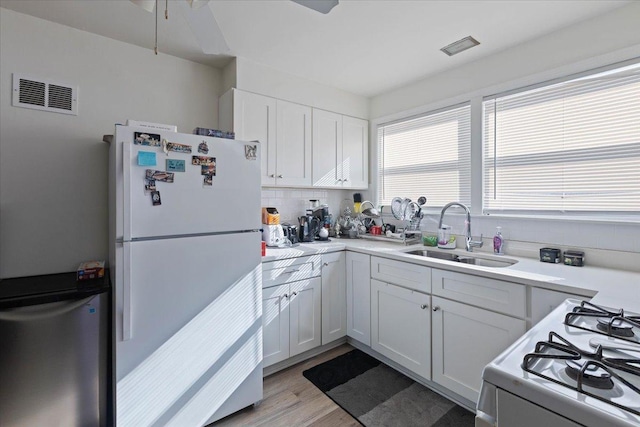 kitchen featuring a sink, visible vents, light countertops, and white appliances