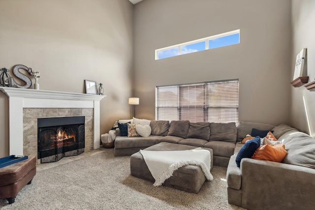 living room with a tiled fireplace, carpet flooring, and a towering ceiling