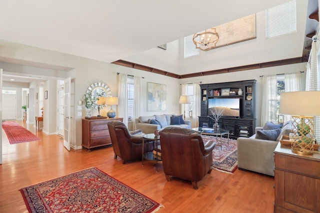 living room with light wood-type flooring, baseboards, and a notable chandelier