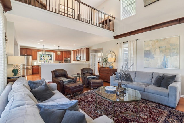 living area featuring a high ceiling, recessed lighting, and light wood-style floors