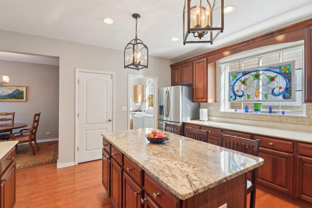 kitchen featuring stainless steel fridge with ice dispenser, a center island, hanging light fixtures, light wood-type flooring, and recessed lighting