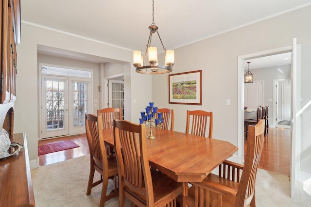 dining room with light wood-style floors, a chandelier, and crown molding