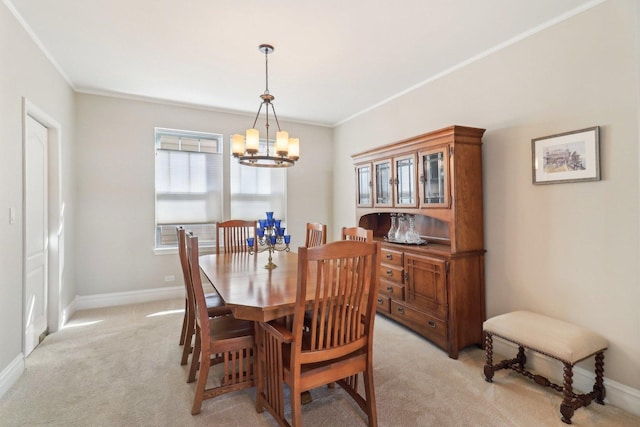 dining room featuring a chandelier, light carpet, ornamental molding, and baseboards