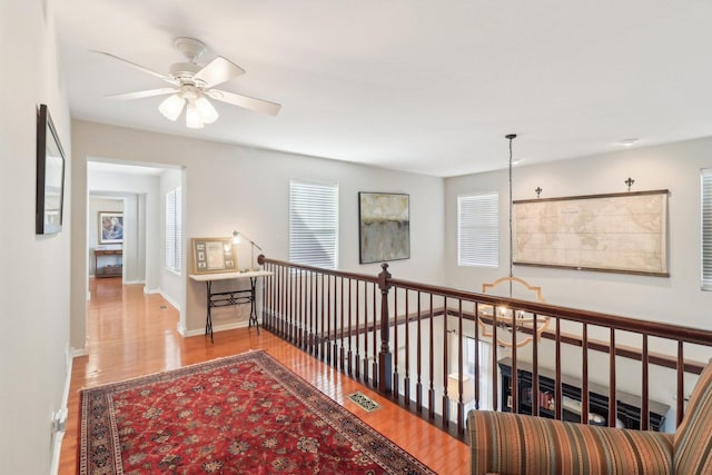 hall featuring wood finished floors, visible vents, and baseboards