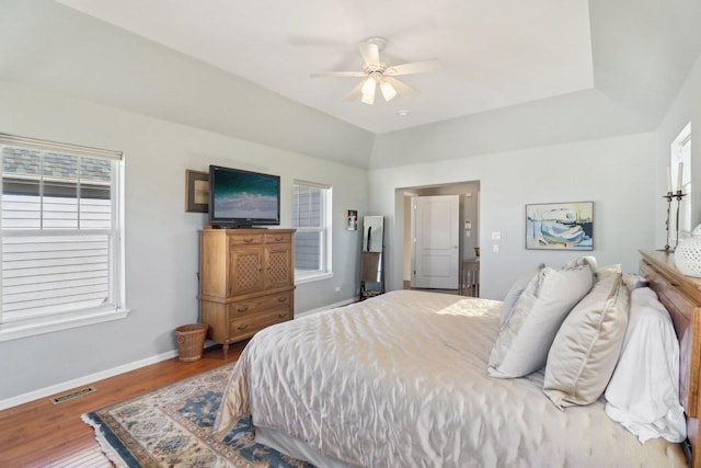 bedroom featuring wood finished floors, visible vents, a ceiling fan, vaulted ceiling, and baseboards